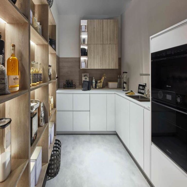 Moderne weiße Küche mit Hochschränken, Holzregal und schwarzen Einbaugeräten – Küche kaufen Freiburg